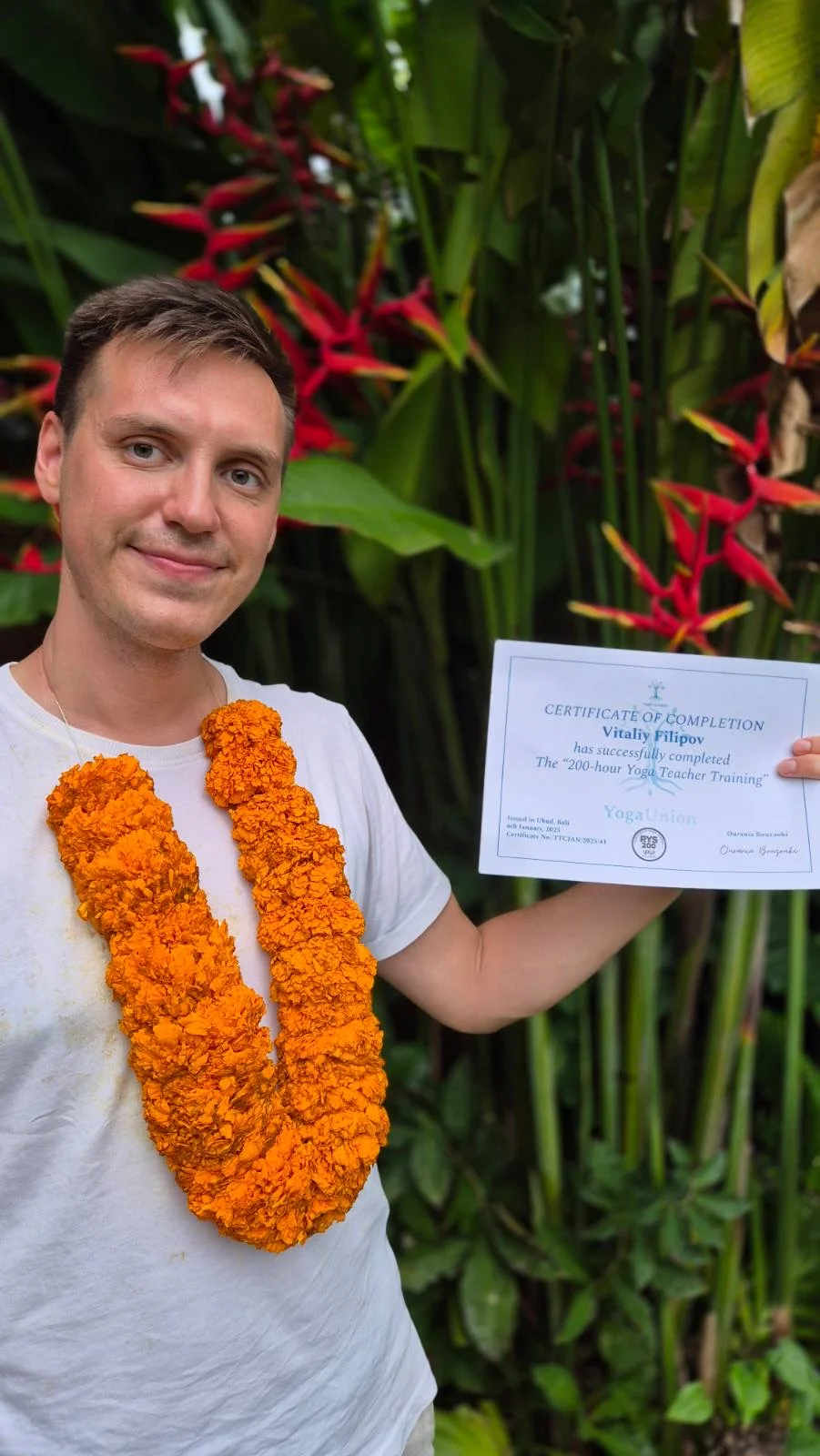 Vitaliy Filipov holding his yoga teacher training certificate